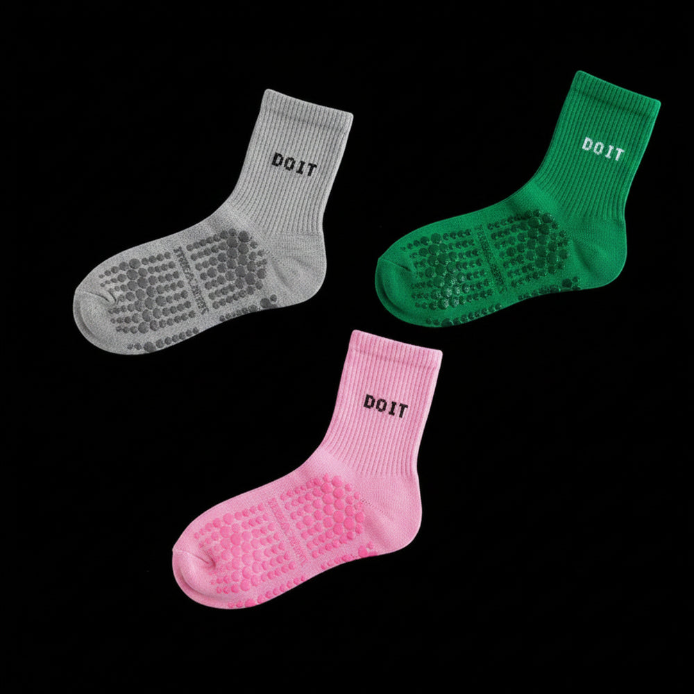 Three pairs of socks in gray, dark green, and light pink on a black studio background.