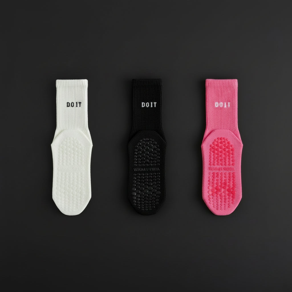 Three pairs of DOIT scrub socks in white, black, and rose red on a black studio b background
