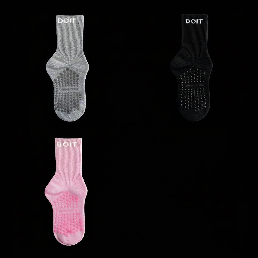 Three pairs of socks in gray, black, and light pink on a stidio black background. removing descriptive text