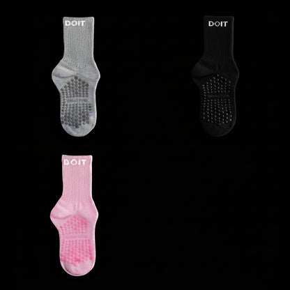 Three pairs of socks in gray, black, and light pink on a stidio black background. removing descriptive text