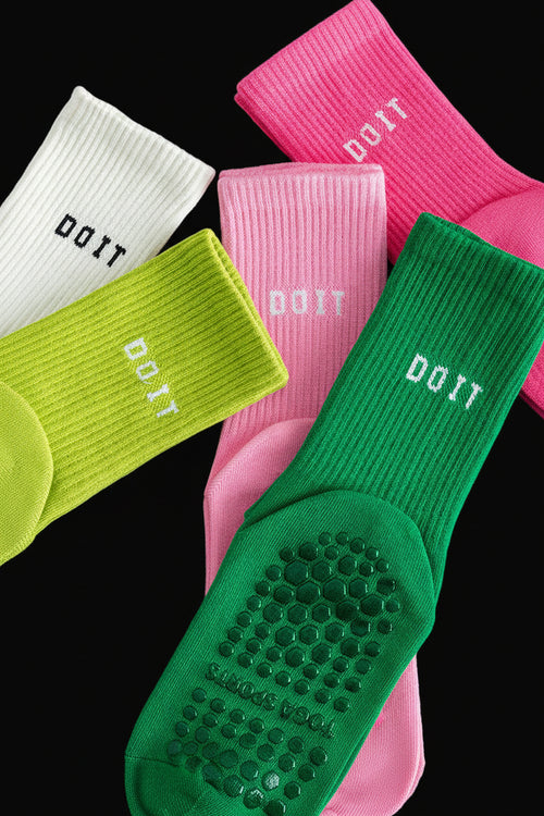 Colorful grip socks with 'DO IT' text on a gray surface black studio background