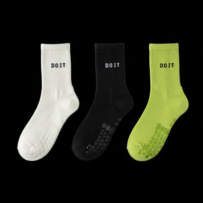 Three pairs of socks in white, black, and light green on a black studio background with 'DOIT' branding. removing descriptive text